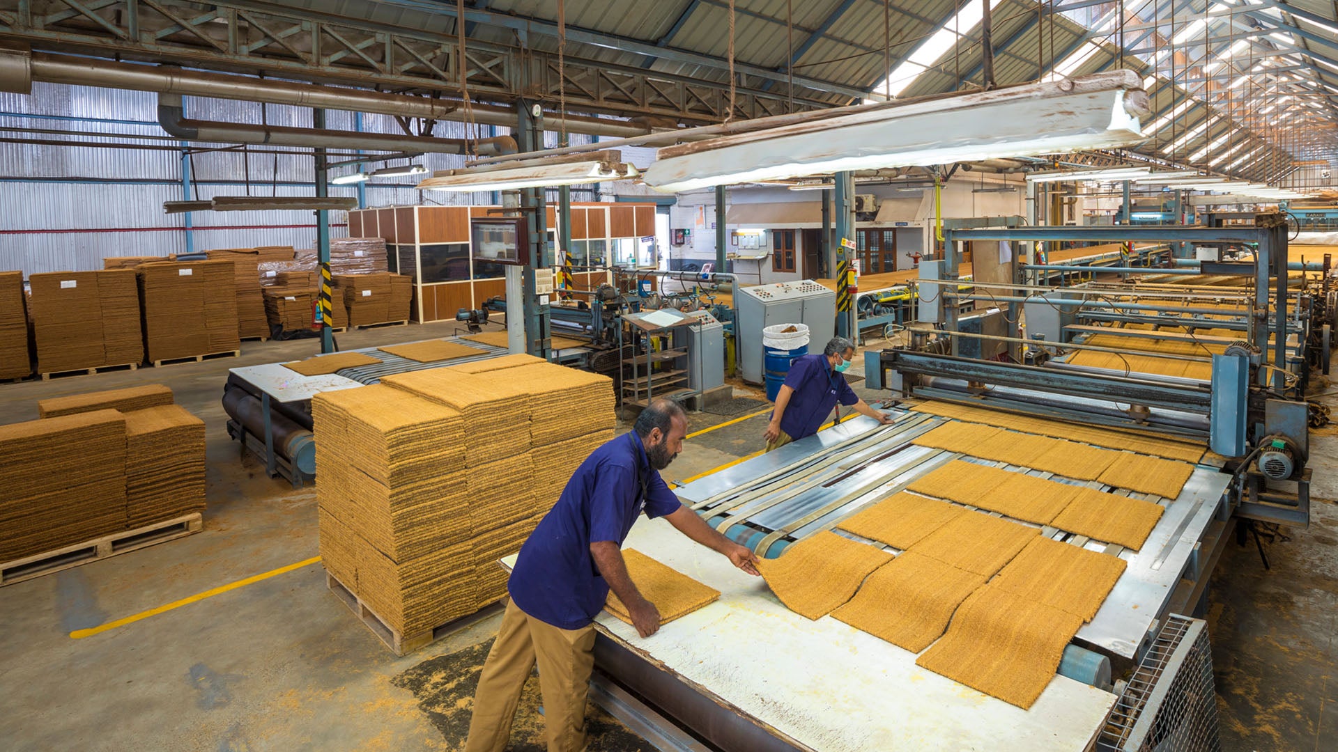 Workers in a warehouse with coir mats and  machinery